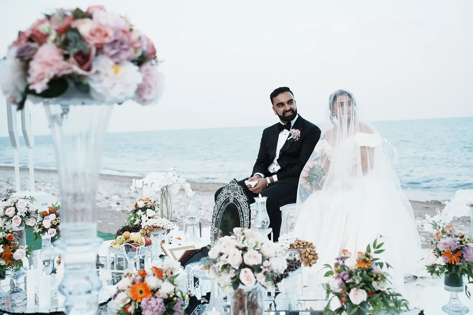 Persian bride and groom seated at their Sofreh Aghd beside the Mediterranean Sea in Antalya