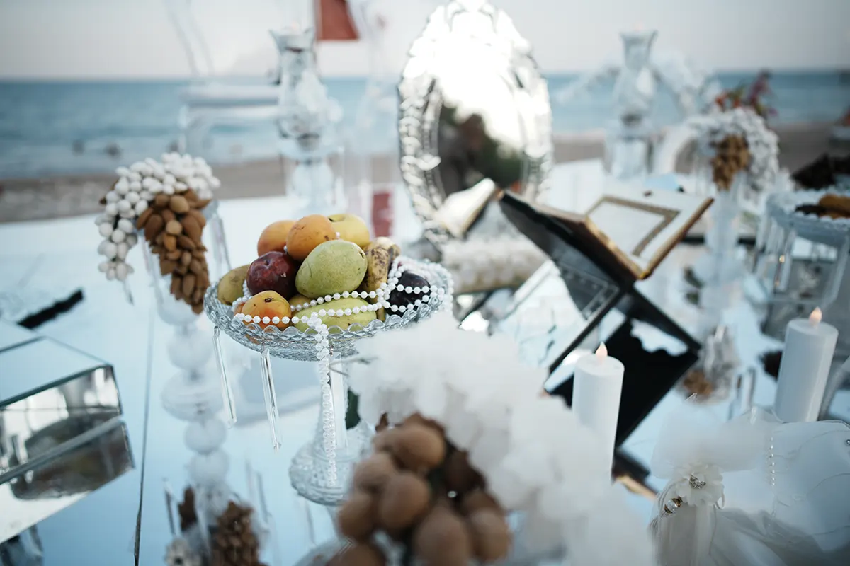 Traditional Sofreh Aghd details featuring fruit, mirror, candles and wedding decorations beside the sea in Antalya