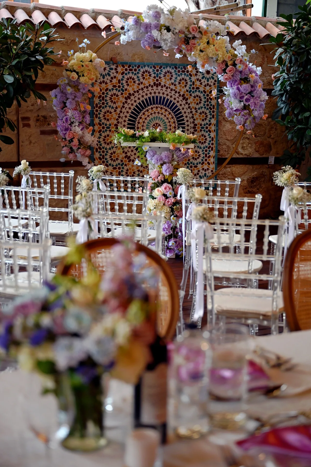 Intimate wedding ceremony setting in Antalya Old Town with lilac and pink floral arch, patterned tiled wall and clear chairs