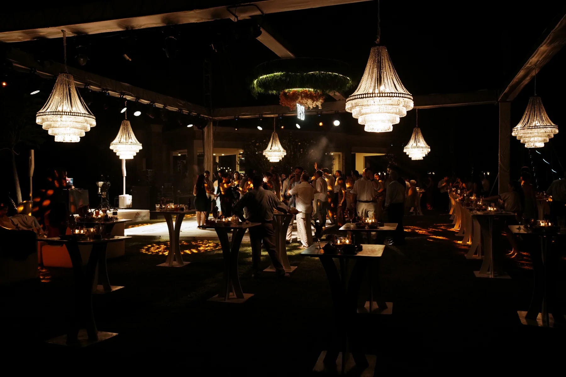 Wedding guests celebrating at an evening reception in Antalya beneath illuminated chandeliers, coordinated by Ramarossi.