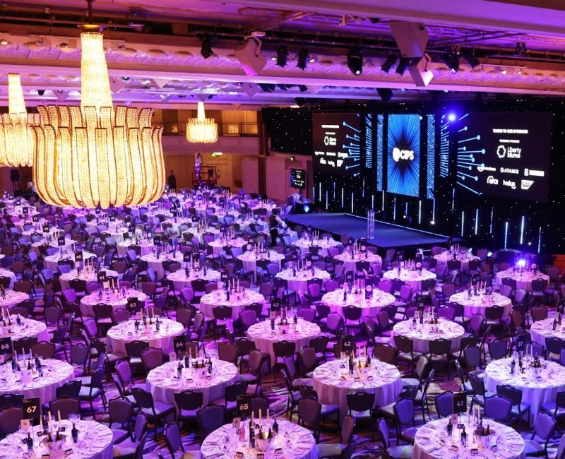 Corporate gala ballroom with stage, presentation screens and round-table seating