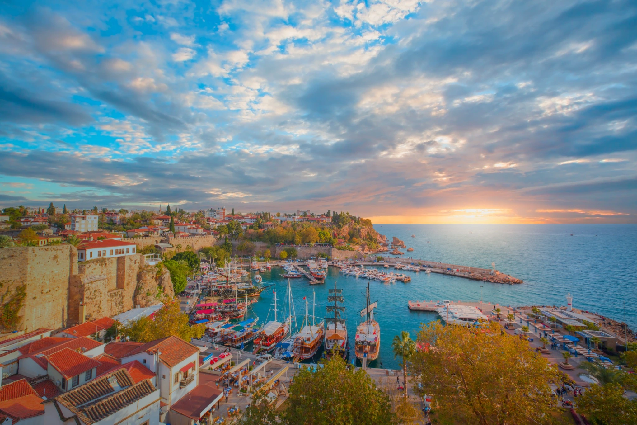 Kaleiçi Old Harbour in Antalya at sunset, with waterfront buildings and boats.