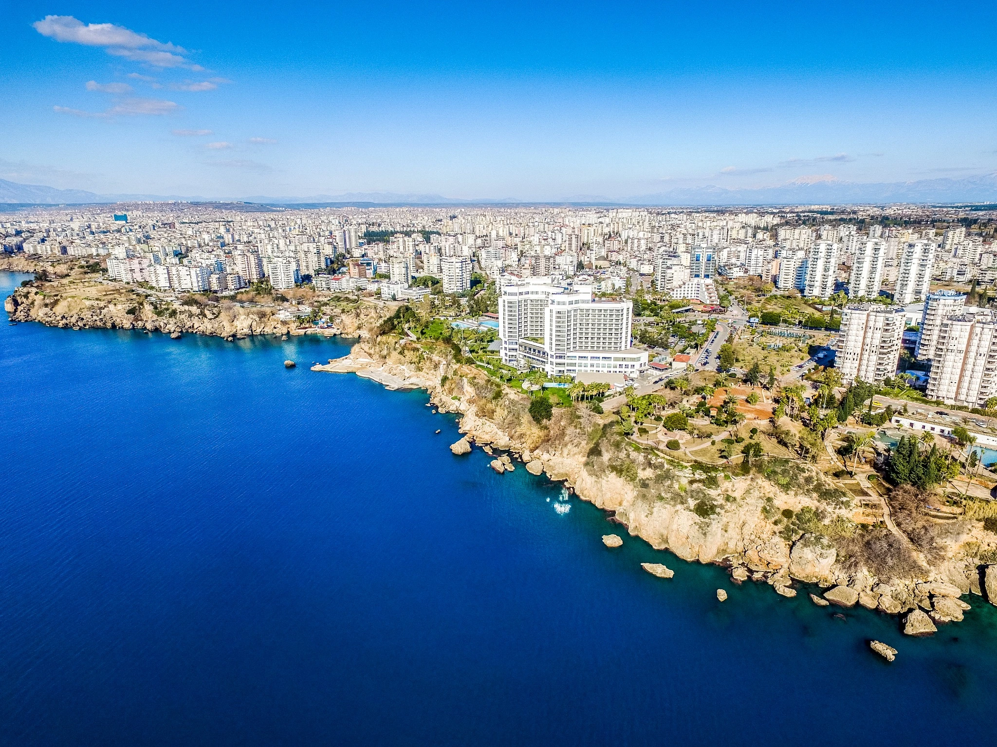 Aerial view of Antalya's Mediterranean coastline with city cliffs and waterfront buildings.