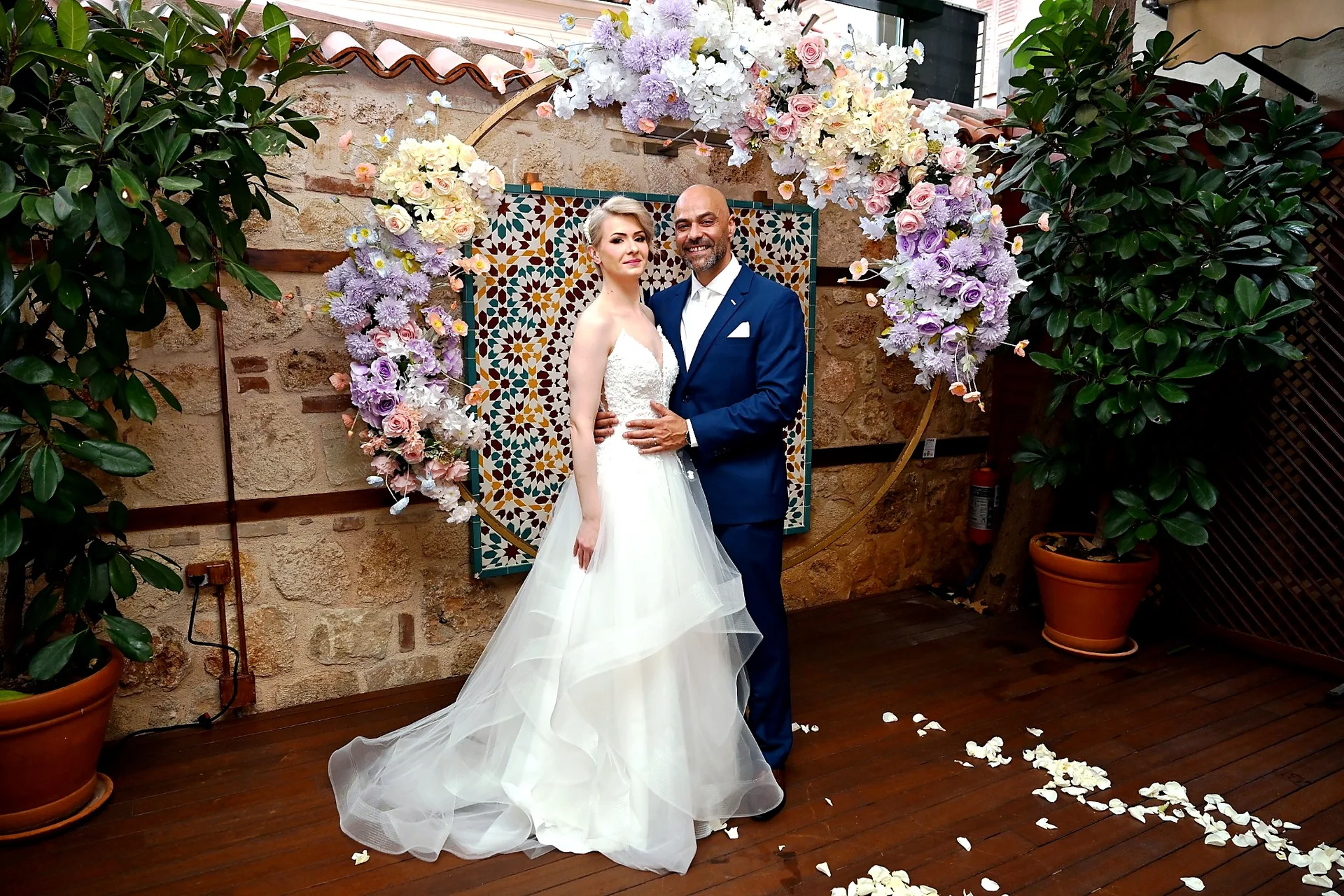 Bride and groom standing together beside a floral wedding arch in Antalya Old Town