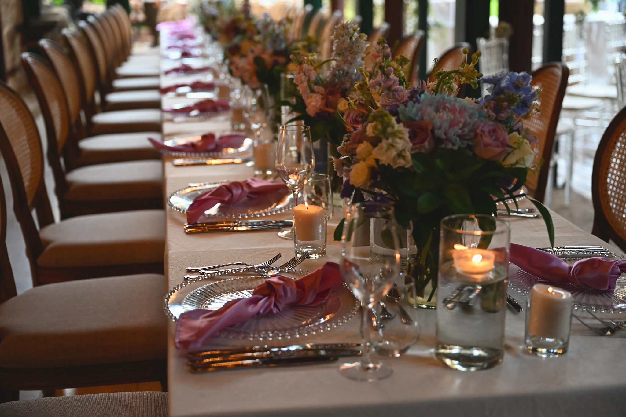 Wedding reception tables in Antalya decorated with pastel floral centrepieces and pink napkins.