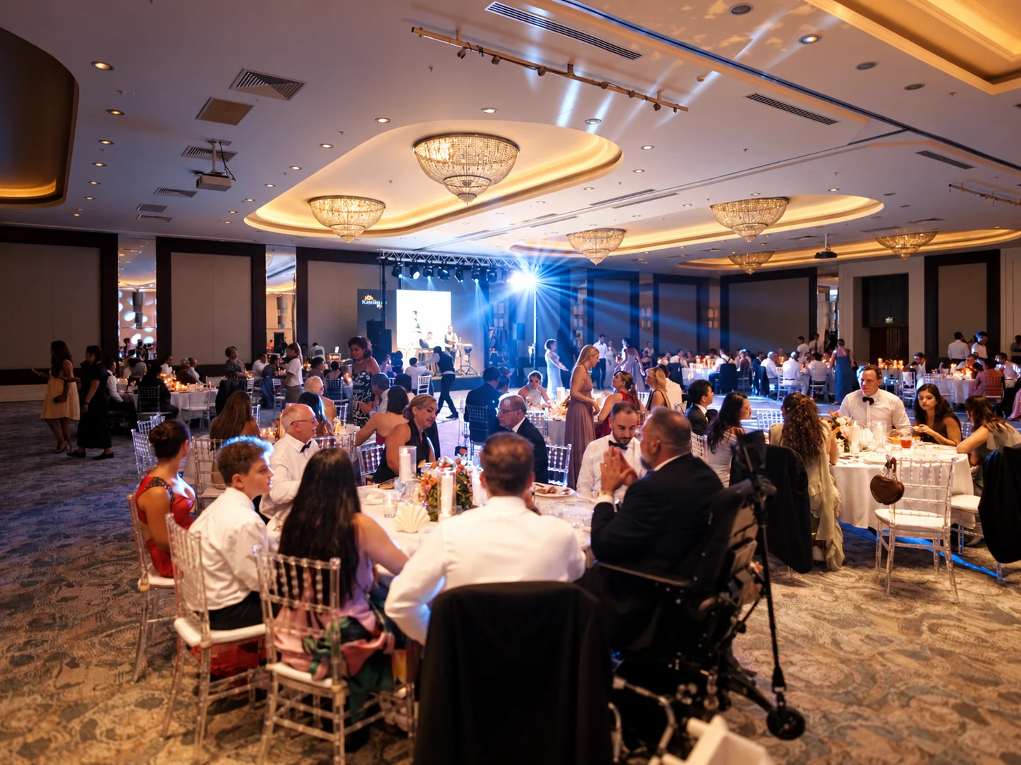 Wedding guests enjoying an indoor ballroom reception with dinner tables and live entertainment in Antalya