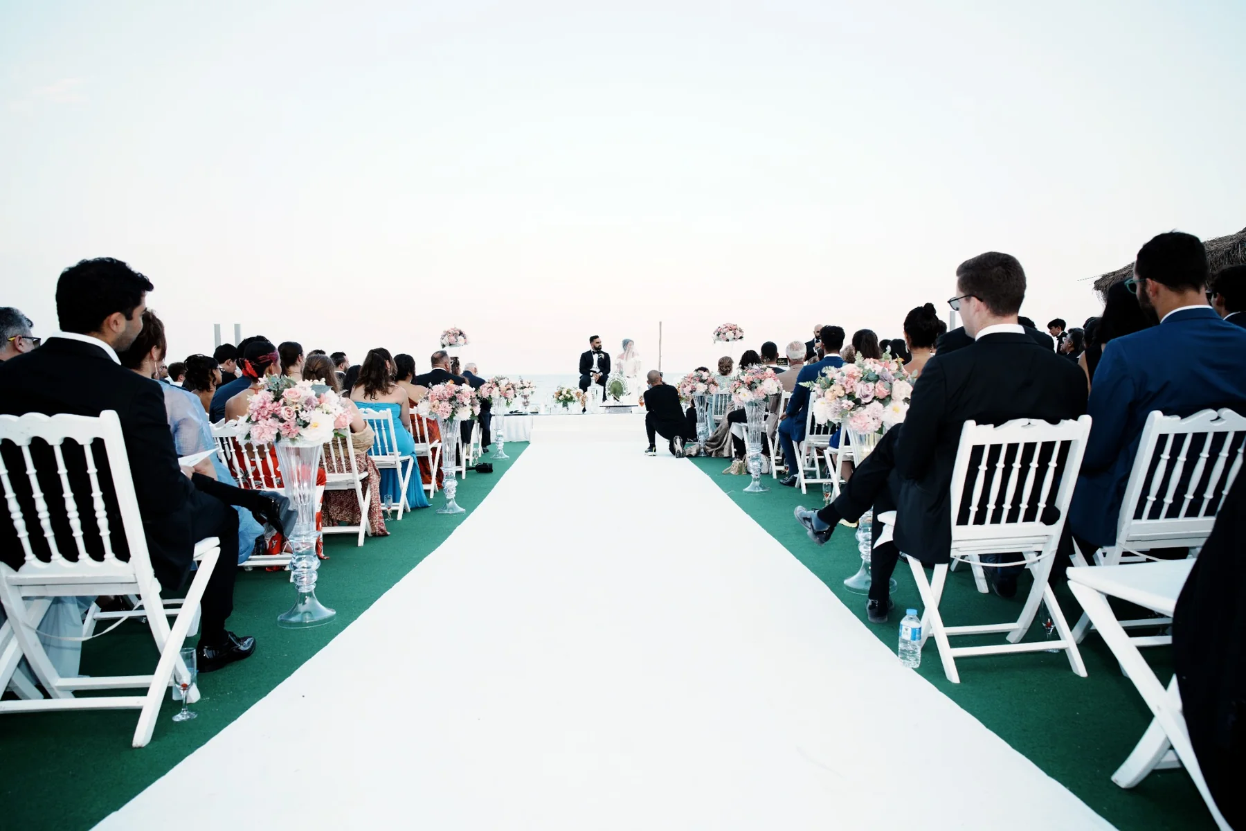 Guests seated along a white aisle at a seaside wedding in Antalya planned by Ramarossi